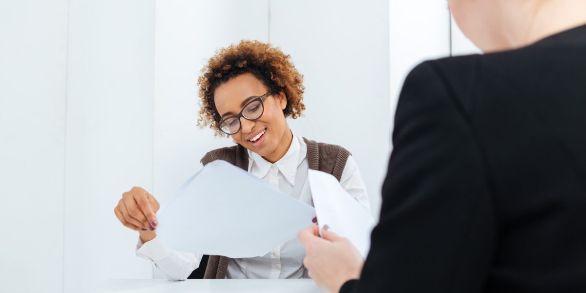 Smiling african american young businesswoman having job interview and filling application in office