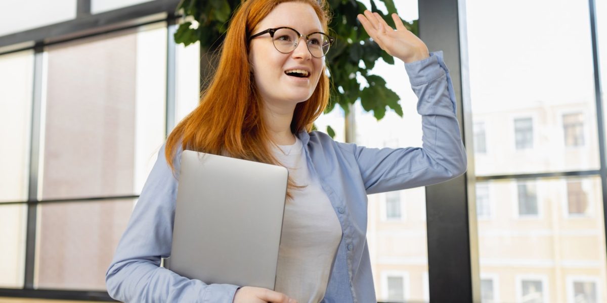 young-caucasian-woman-in-blue-shirt-in-bright-office-greets-colleagues-and-partners-in-the-office_t20_E0bVKX (Groot)
